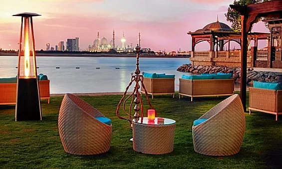 Waterfront lounge terrace at sunset with the Sheikh Zayed Grand Mosque on the skyline