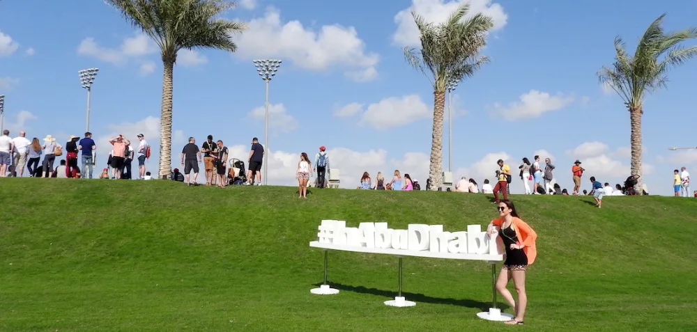 Visitors gathered around the #InAbuDhabi sign on a palm-lined lawn