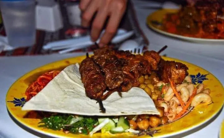 BBQ dinner plate at a Dubai desert safari camp A plate of grilled skewered meats, hummus, salad and flatbread served at a Dubai desert safari camp dinner