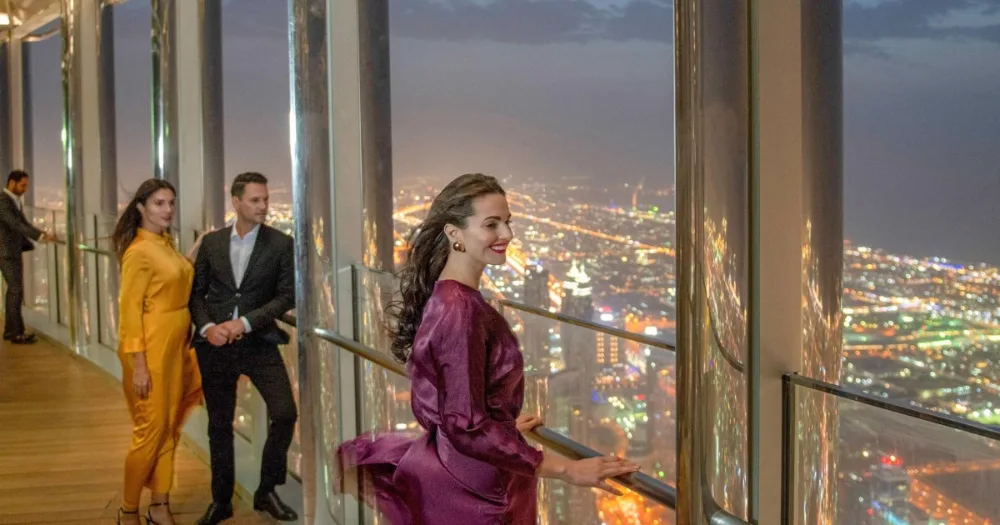 Guests dressed for evening enjoying the night view from Burj Khalifa At The Top