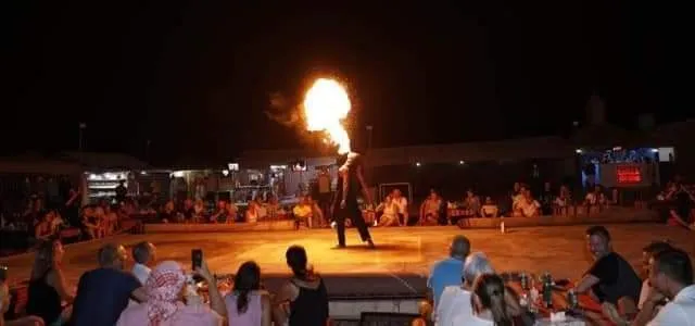 Evening fire show at a Dubai overnight desert safari camp A large fire performance lighting up the night sky in front of a seated crowd at a desert camp