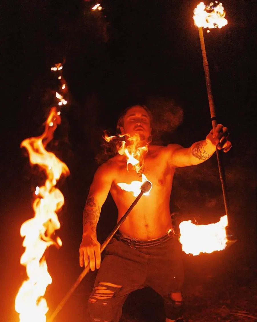 Fire show at a Dubai desert safari camp A fire performer holding two flaming torches during a live show at a Dubai desert safari camp at night