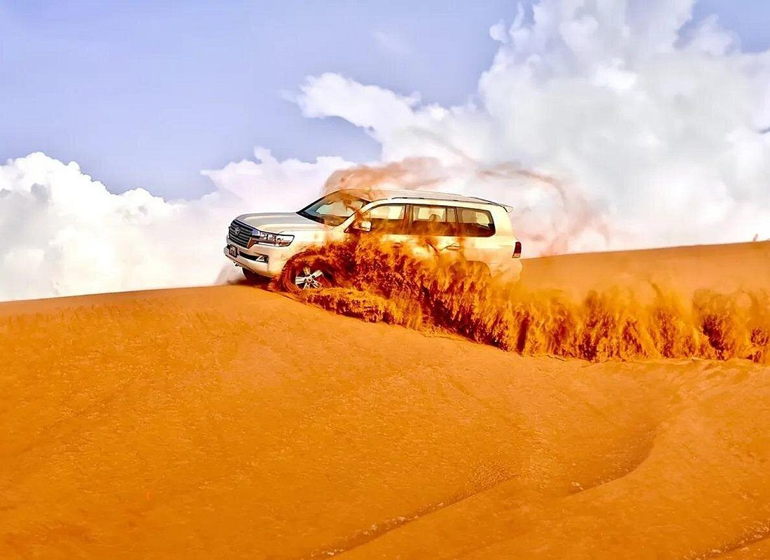 A private 4x4 desert safari vehicle parked alone on a dune with no other groups nearby