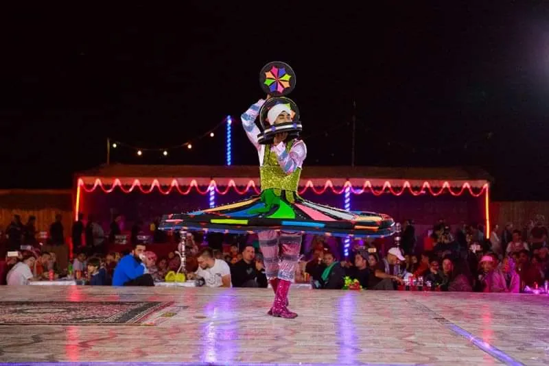Evening entertainment at a Dubai VIP desert safari camp A tanoura dancer in an illuminated LED skirt performing at night in a decorated Dubai desert safari camp