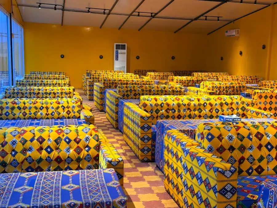 Rows of traditional Arabic majlis seating in the indoor VIP hall at the desert camp