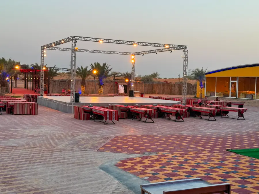 VIP desert safari Dubai camp at dusk with the main stage, Arabic seating and lit majlis lounge